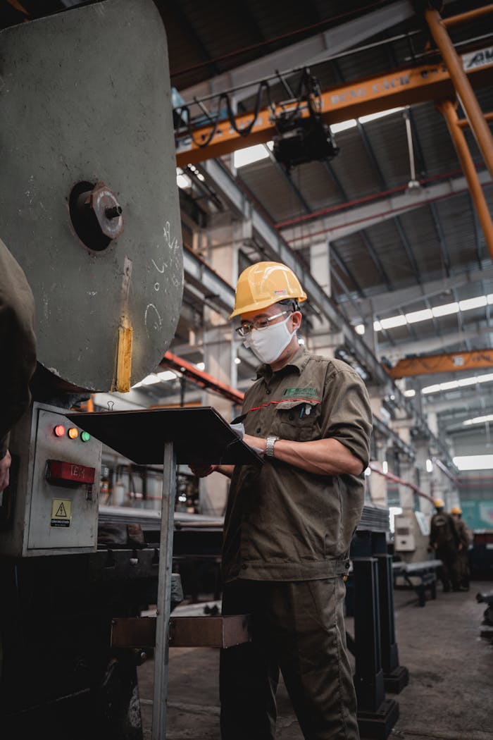 why-choose-us Factory worker with safety gear checks machinery, ensuring industrial safety compliance.