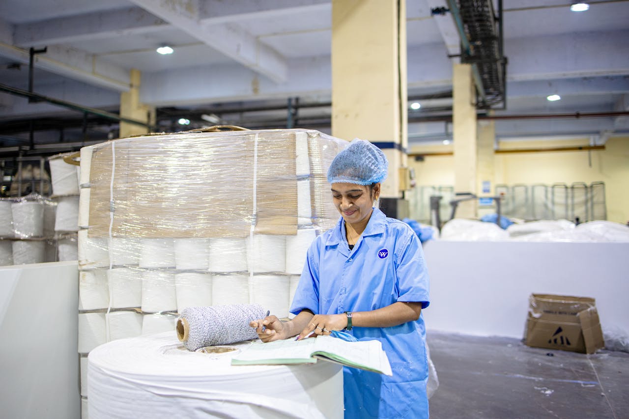 A factory worker records details in a textile manufacturing plant, showcasing industry and precision.