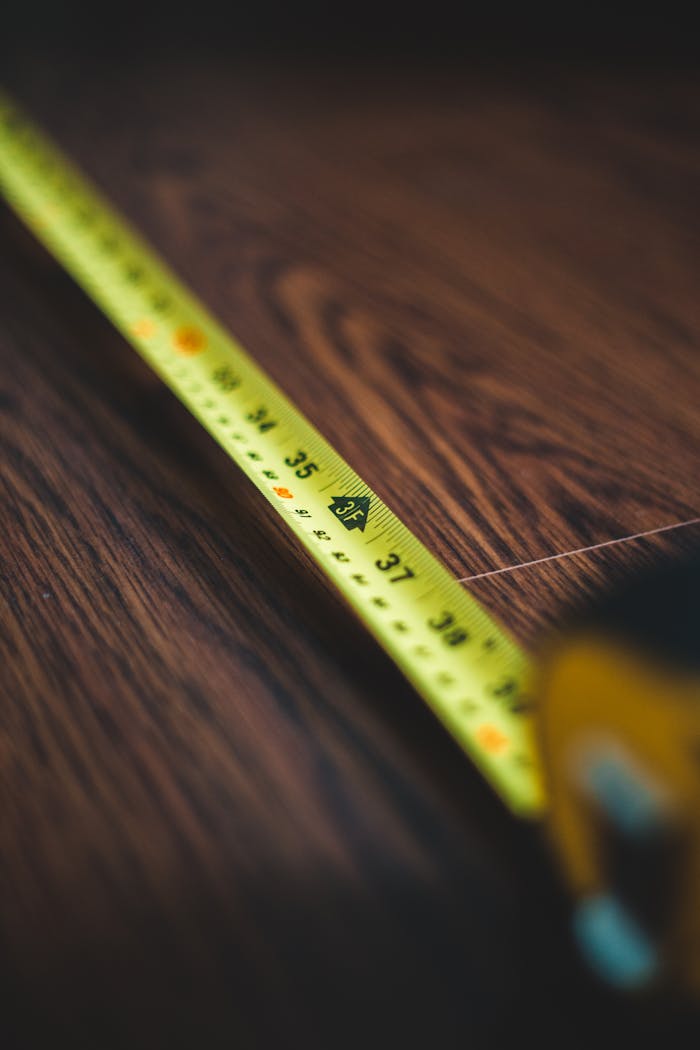 Detailed photo of a yellow measuring tape stretched across a wooden table, depicting precision.